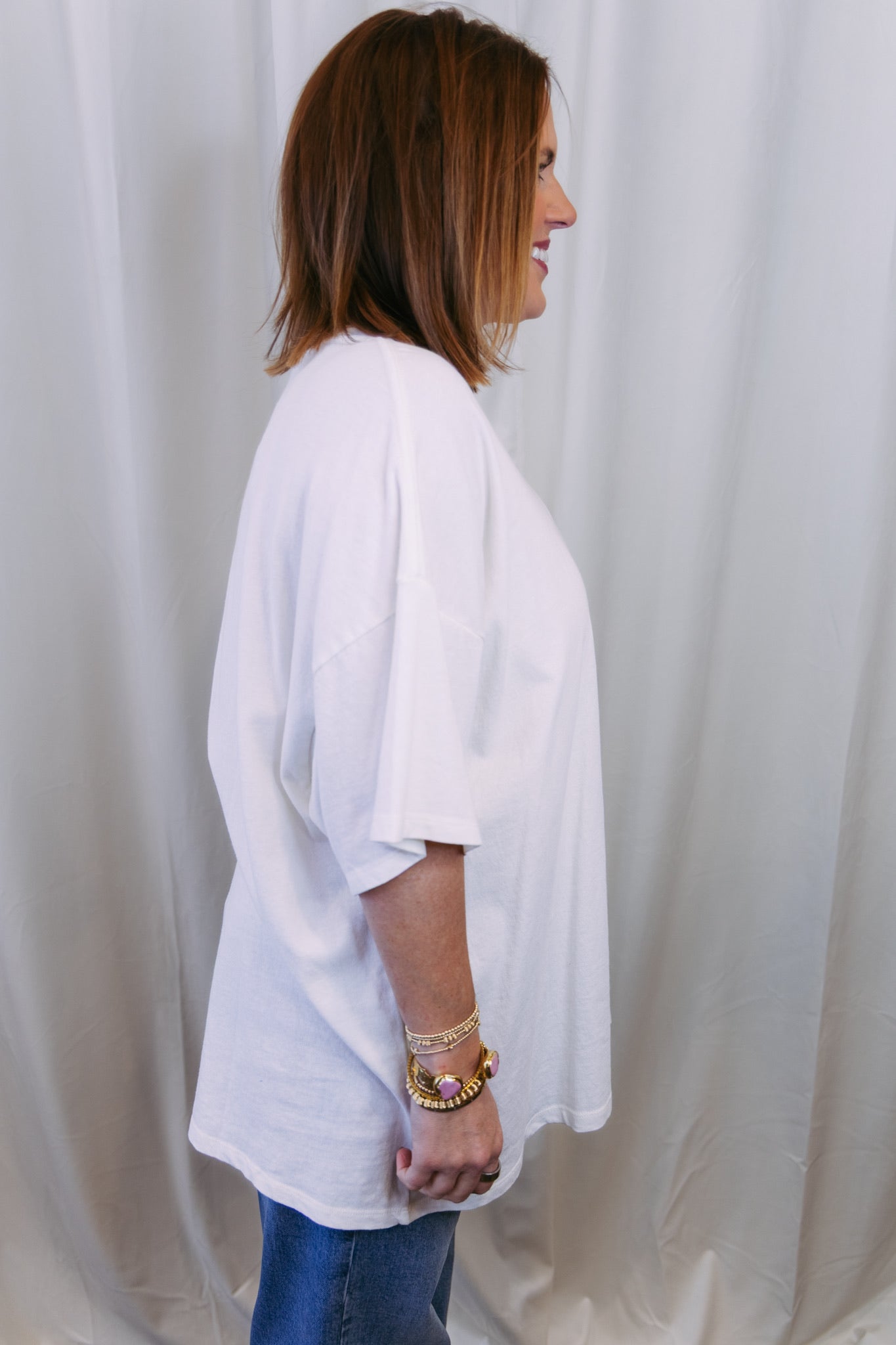 Person wearing a white oversized shirt against a plain background