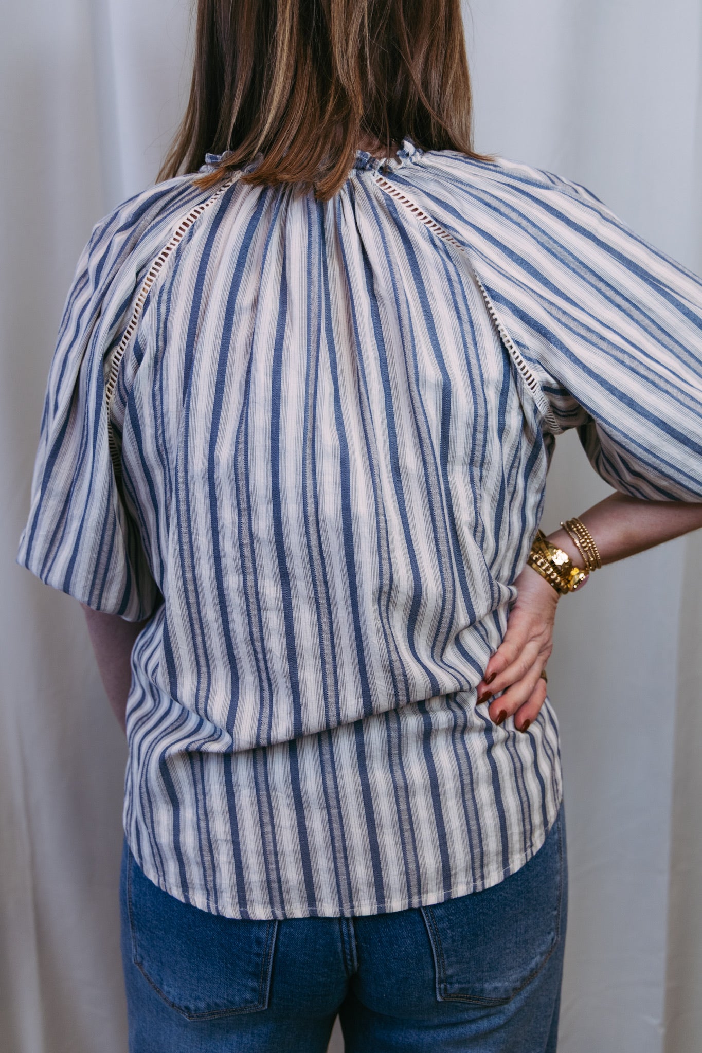 Person wearing a blue and white striped shirt with a plain background