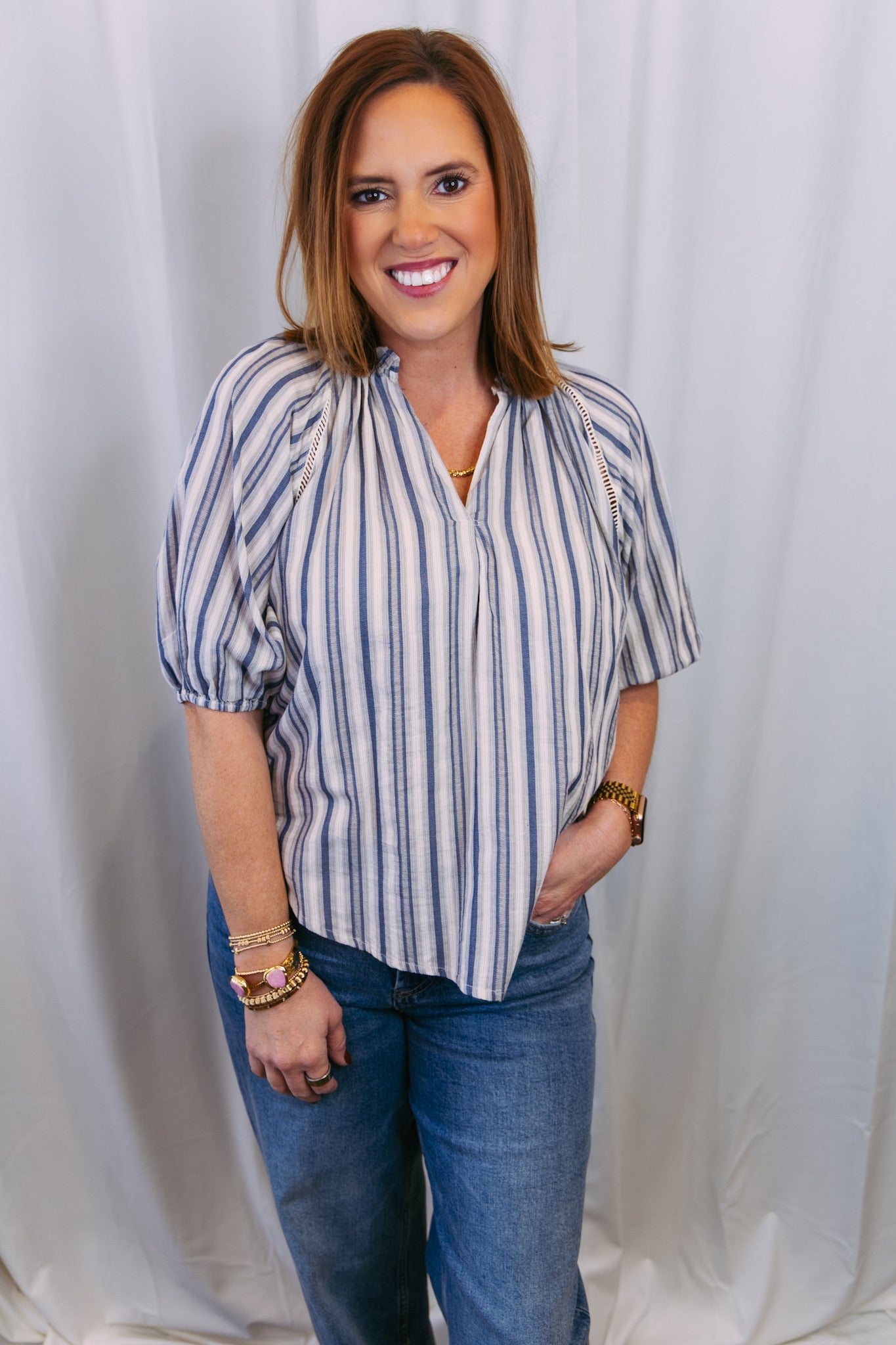 Woman wearing a striped blouse and jeans against a white background