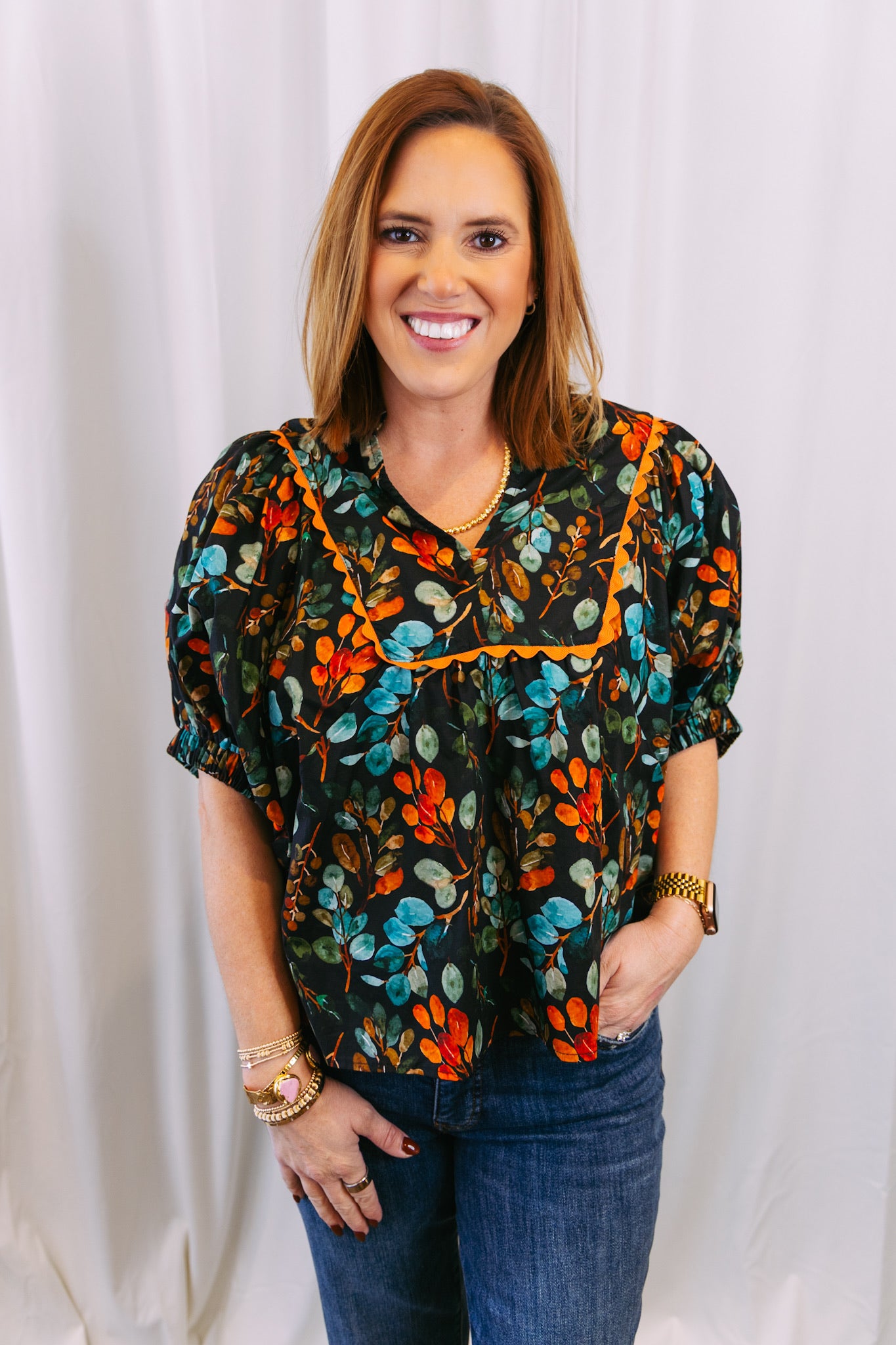 Woman wearing a colorful floral blouse against a white background
