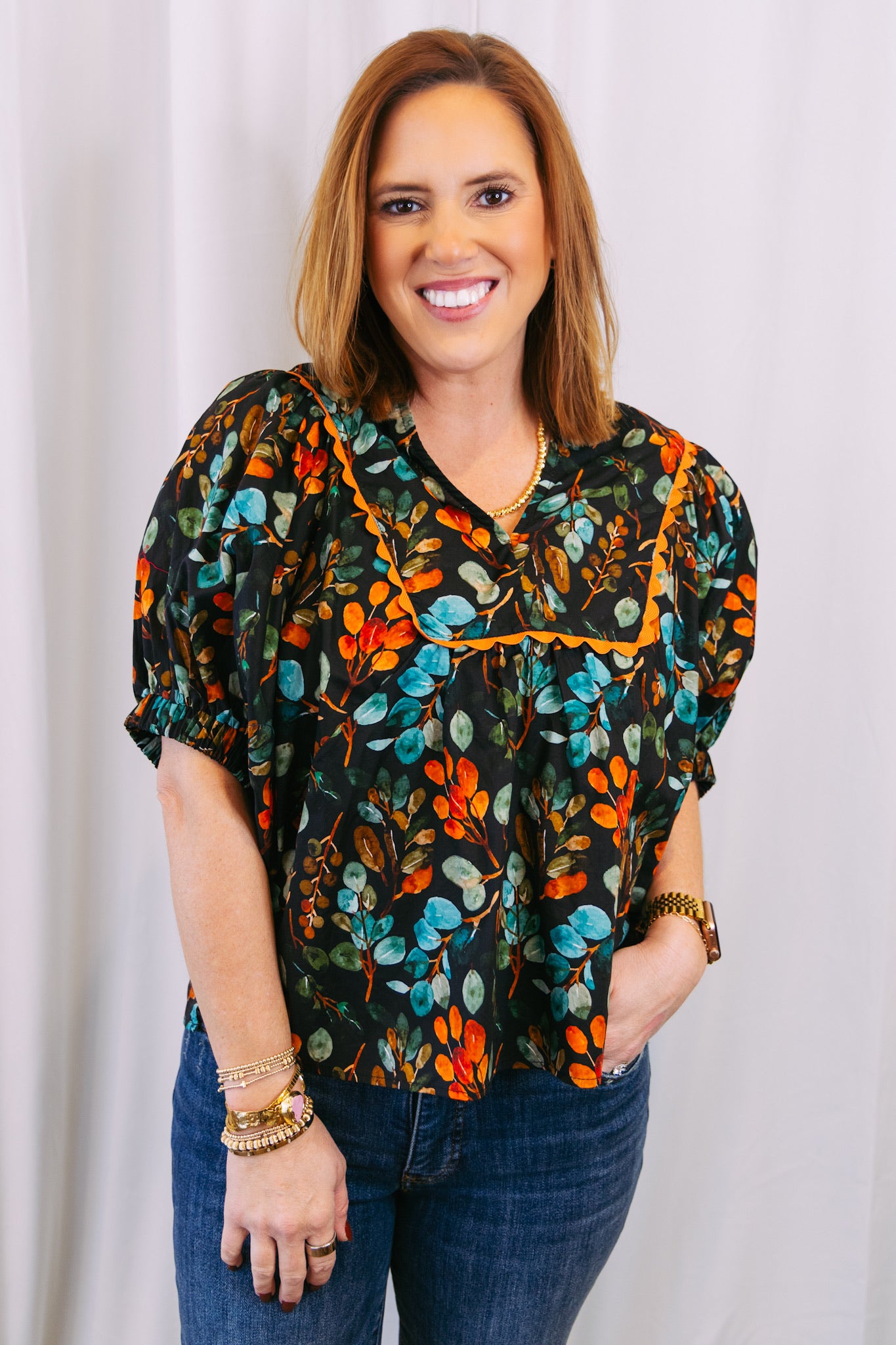 Woman wearing a colorful floral blouse against a plain background