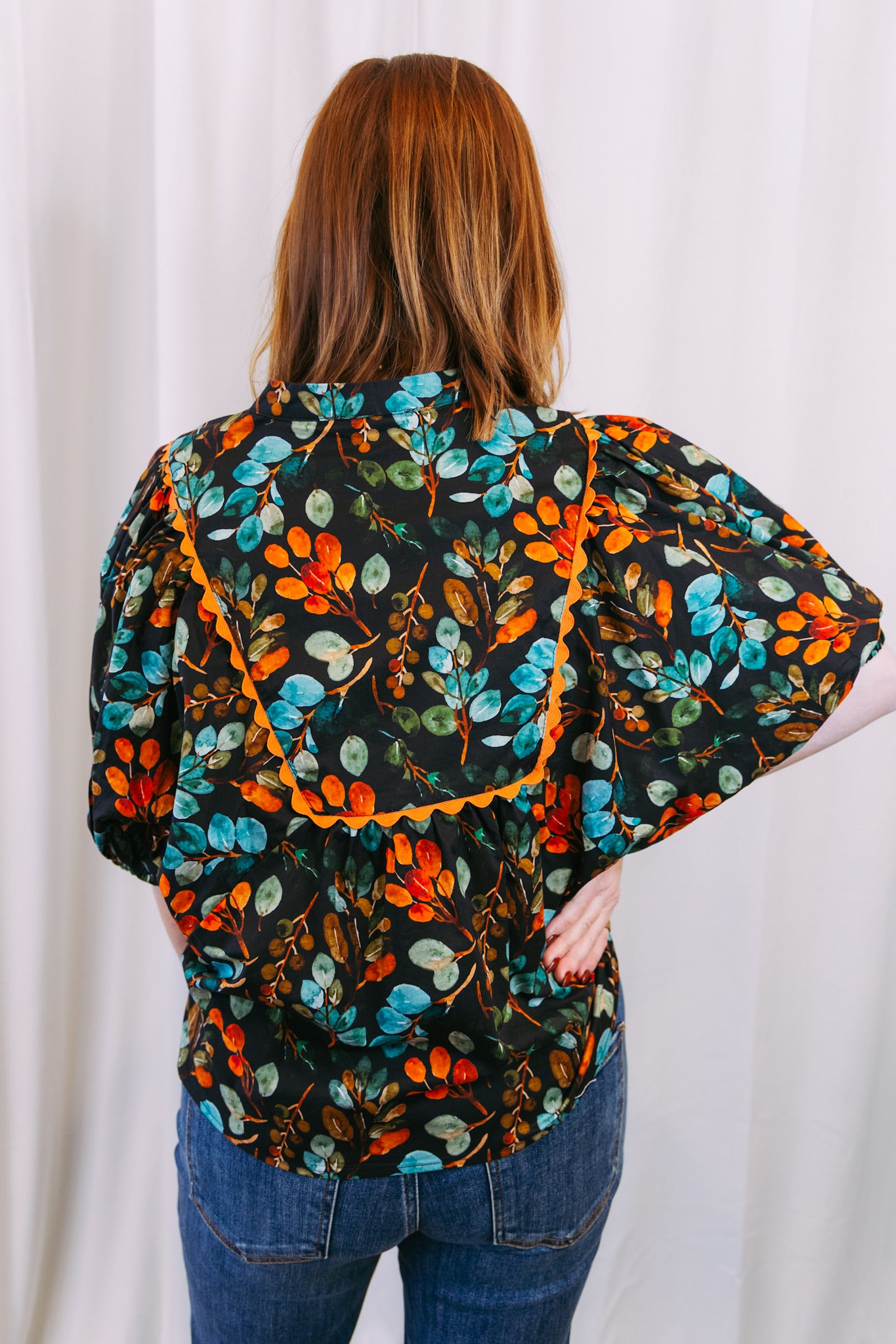 Person wearing a floral blouse with a plain background