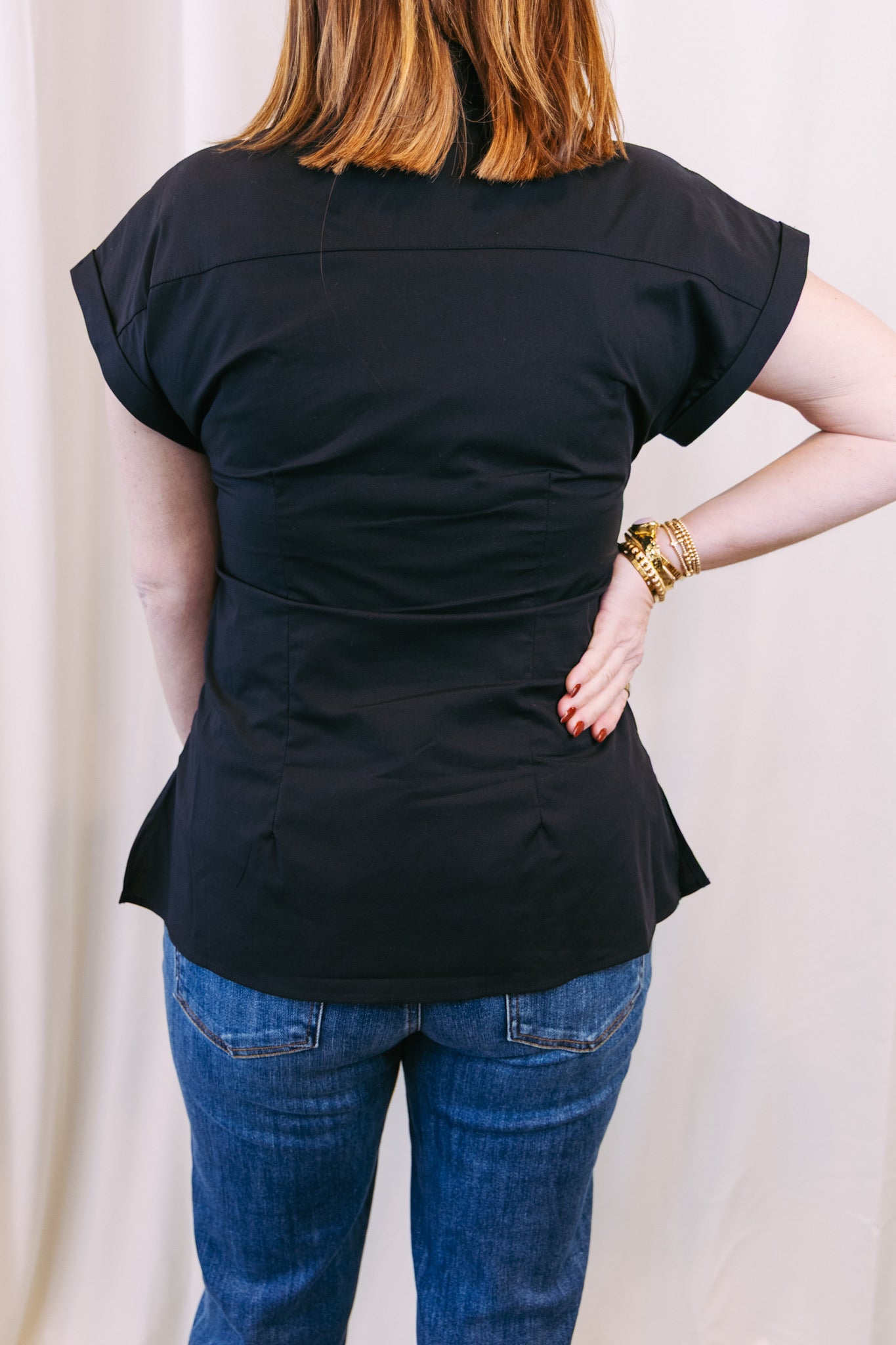 Person wearing a black top and blue jeans with a plain background