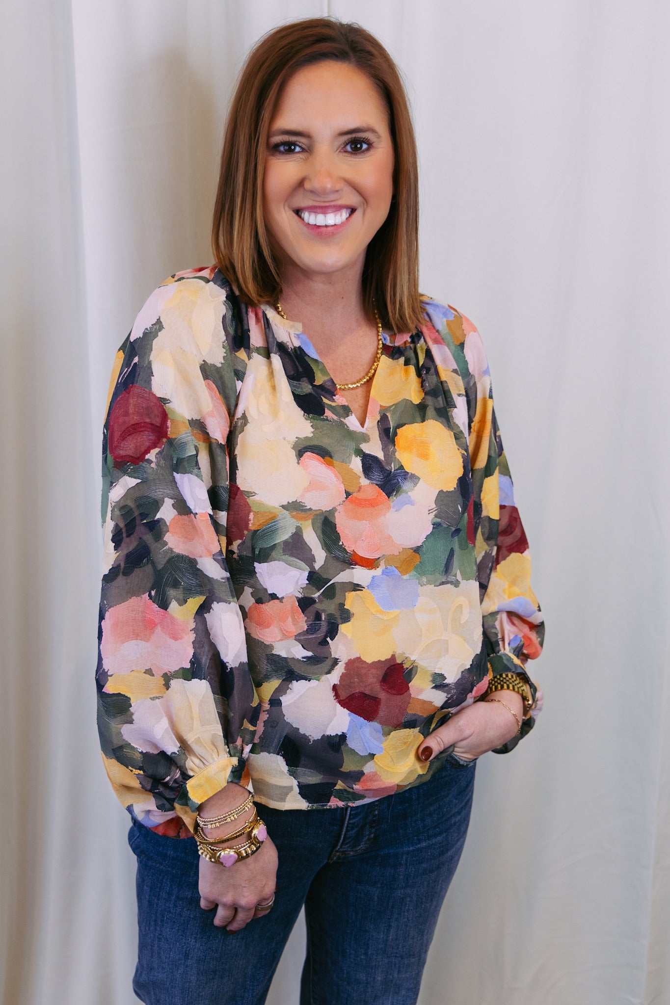 Woman wearing a colorful floral blouse against a white background