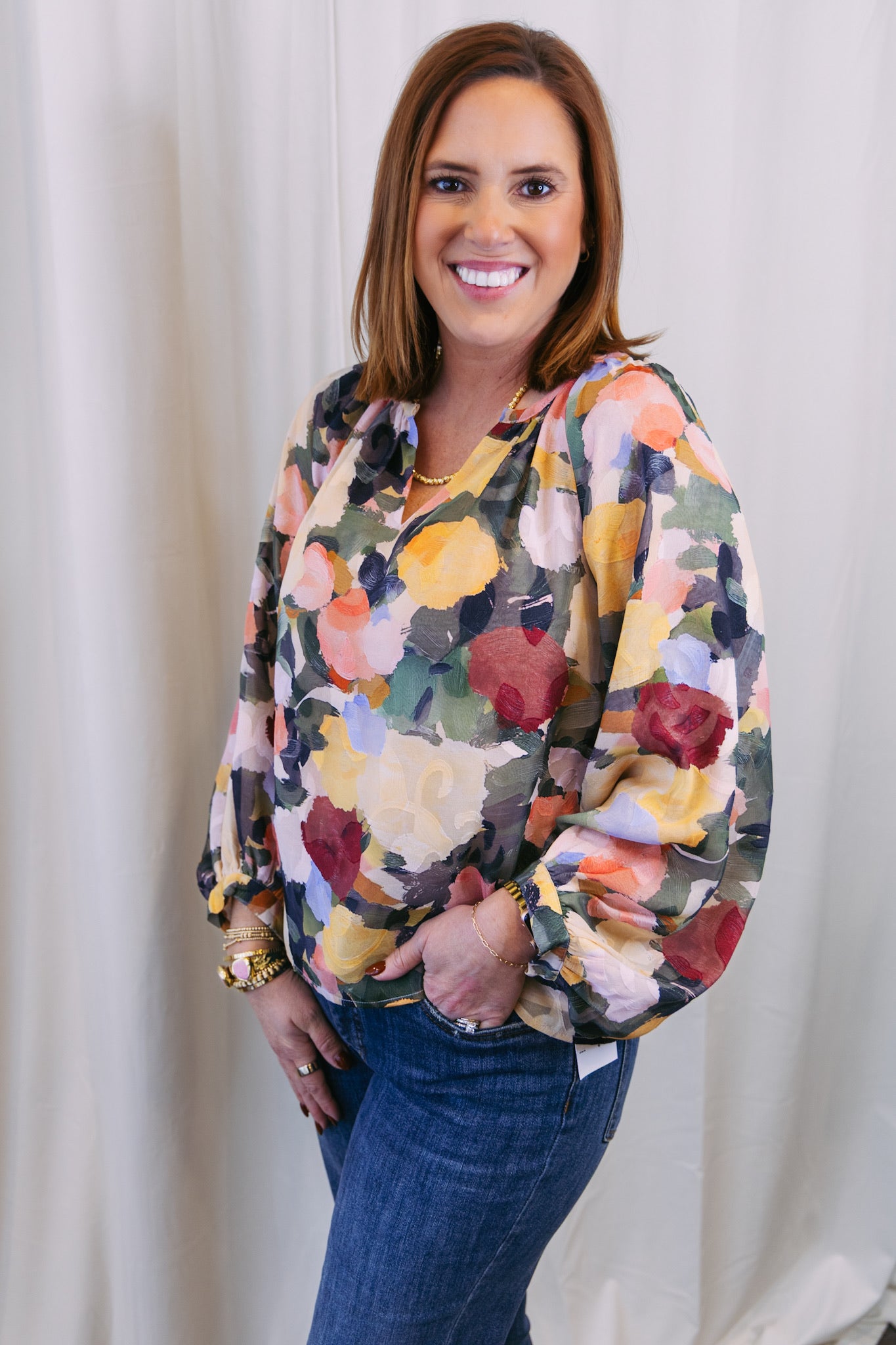 Woman wearing a colorful floral blouse against a white background