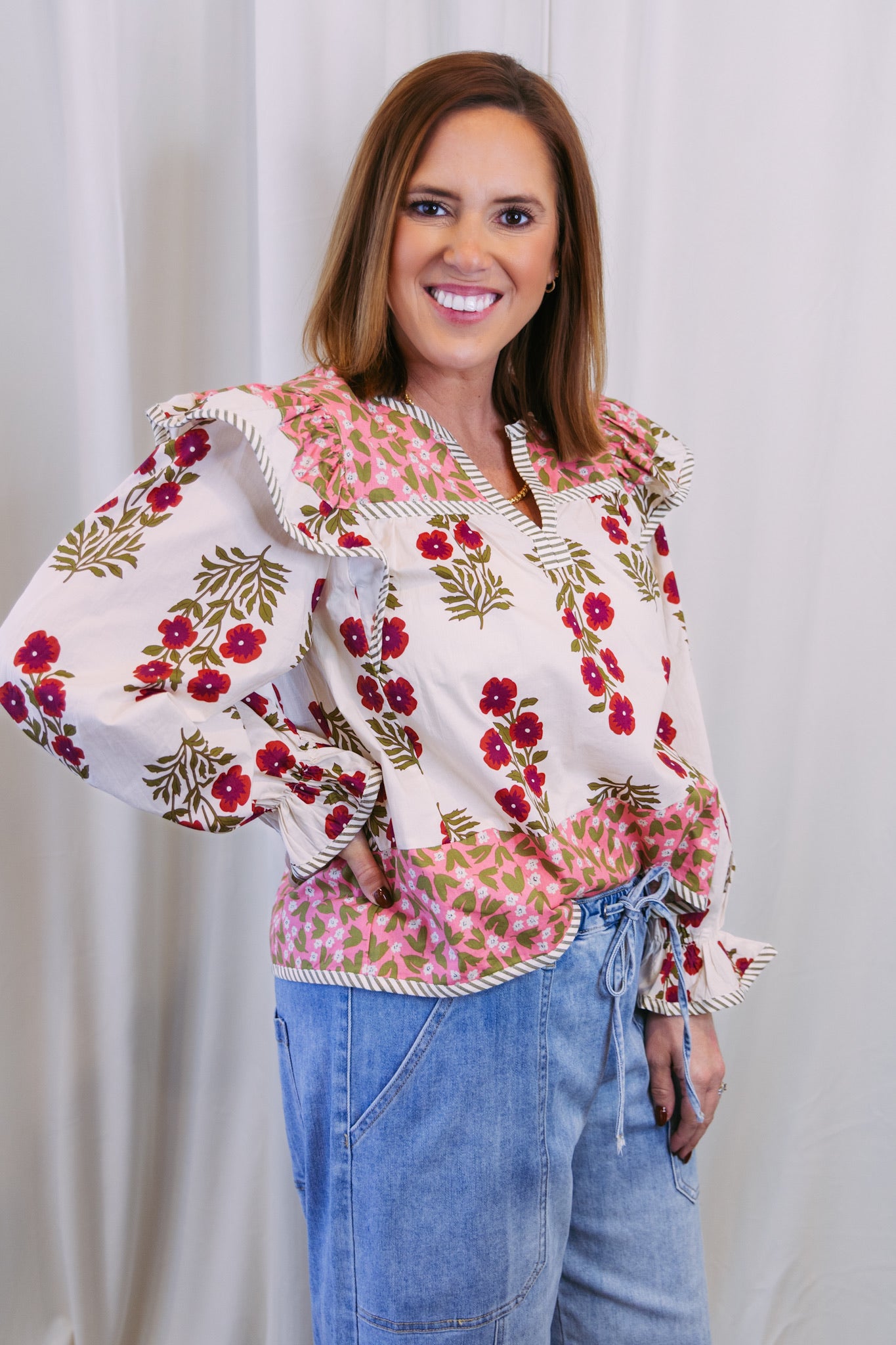 Woman wearing a floral blouse with puffed sleeves against a white background