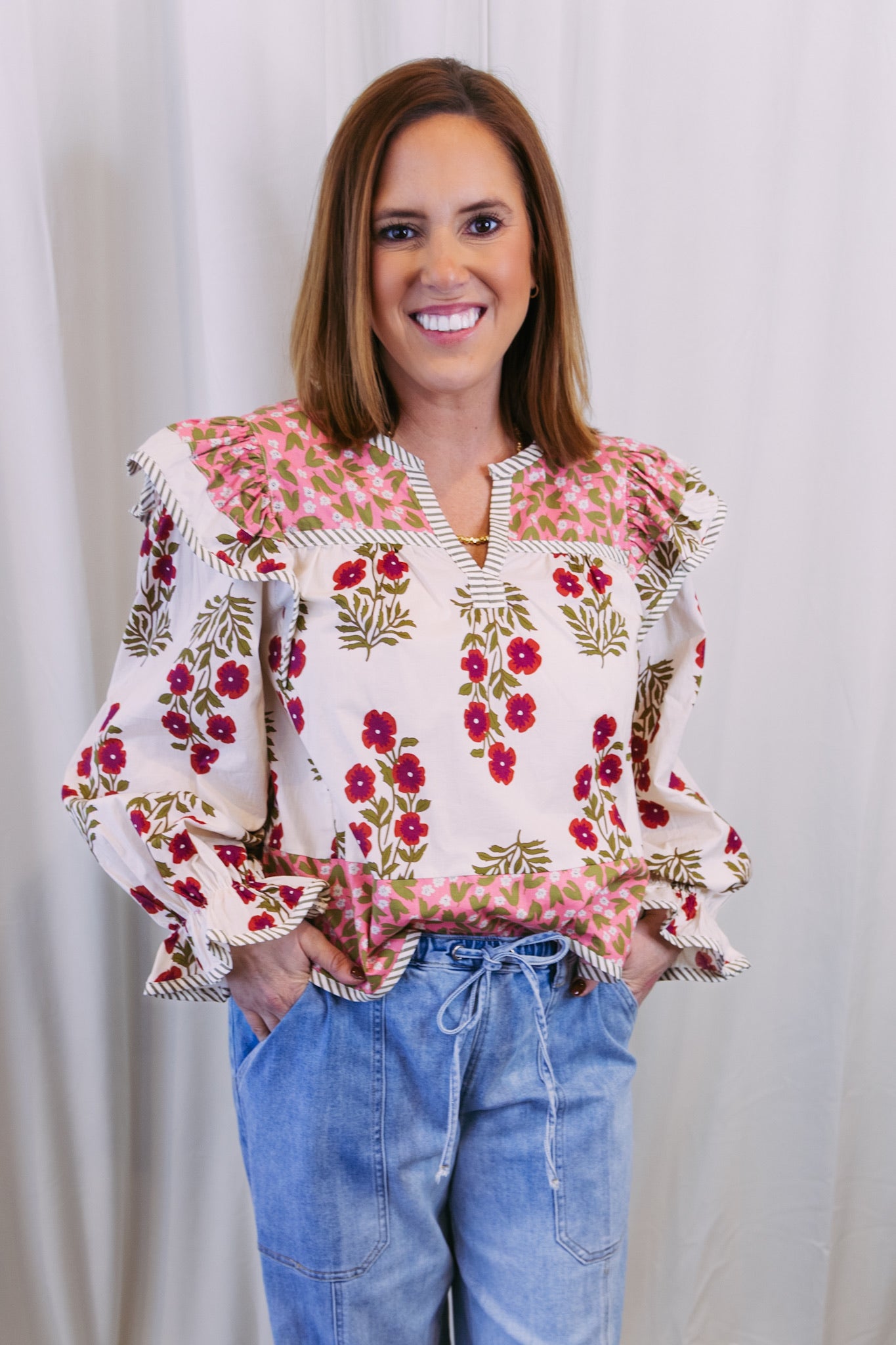 Woman wearing a floral blouse with ruffled sleeves against a plain background