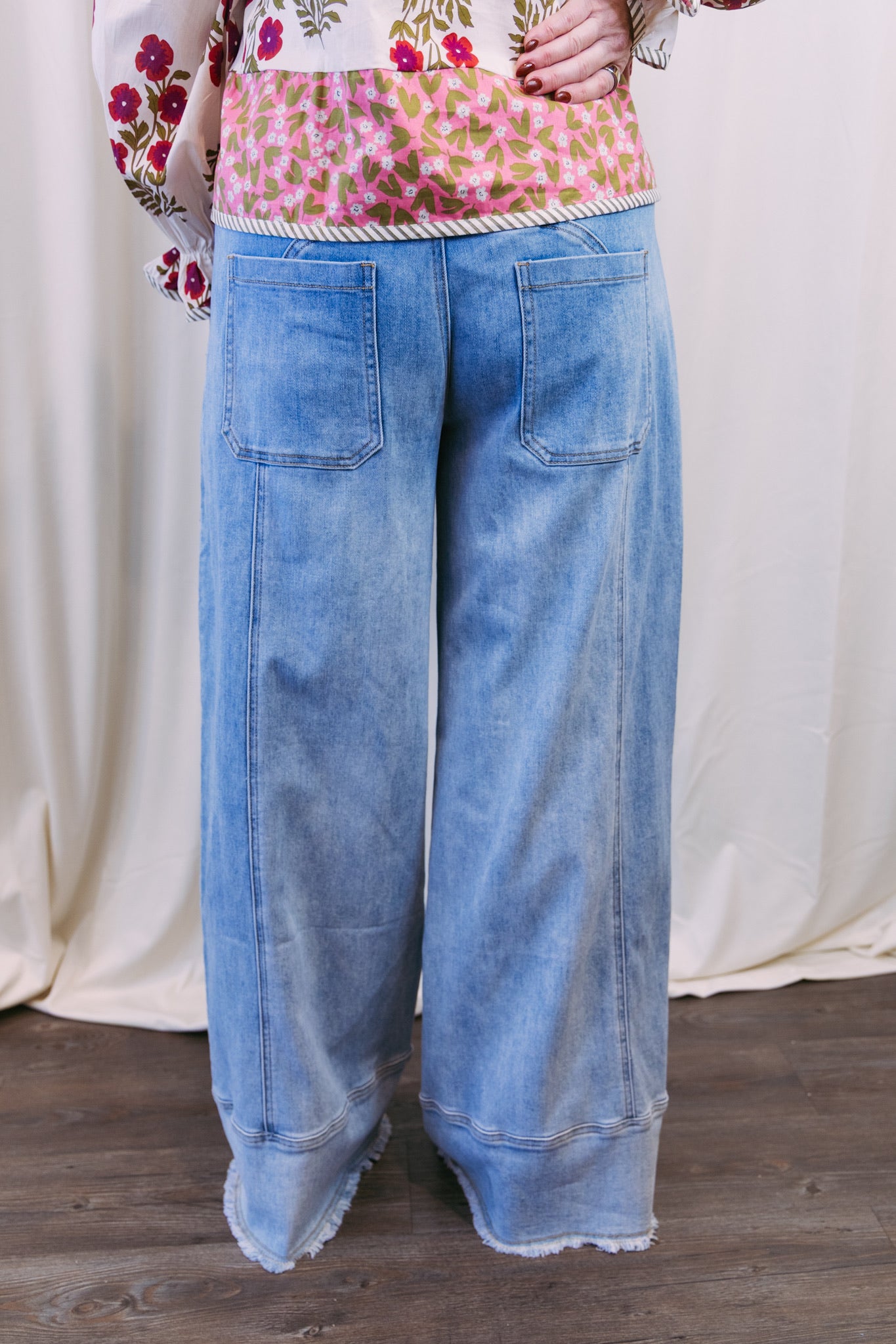 Person wearing a floral top and blue jeans on a white background