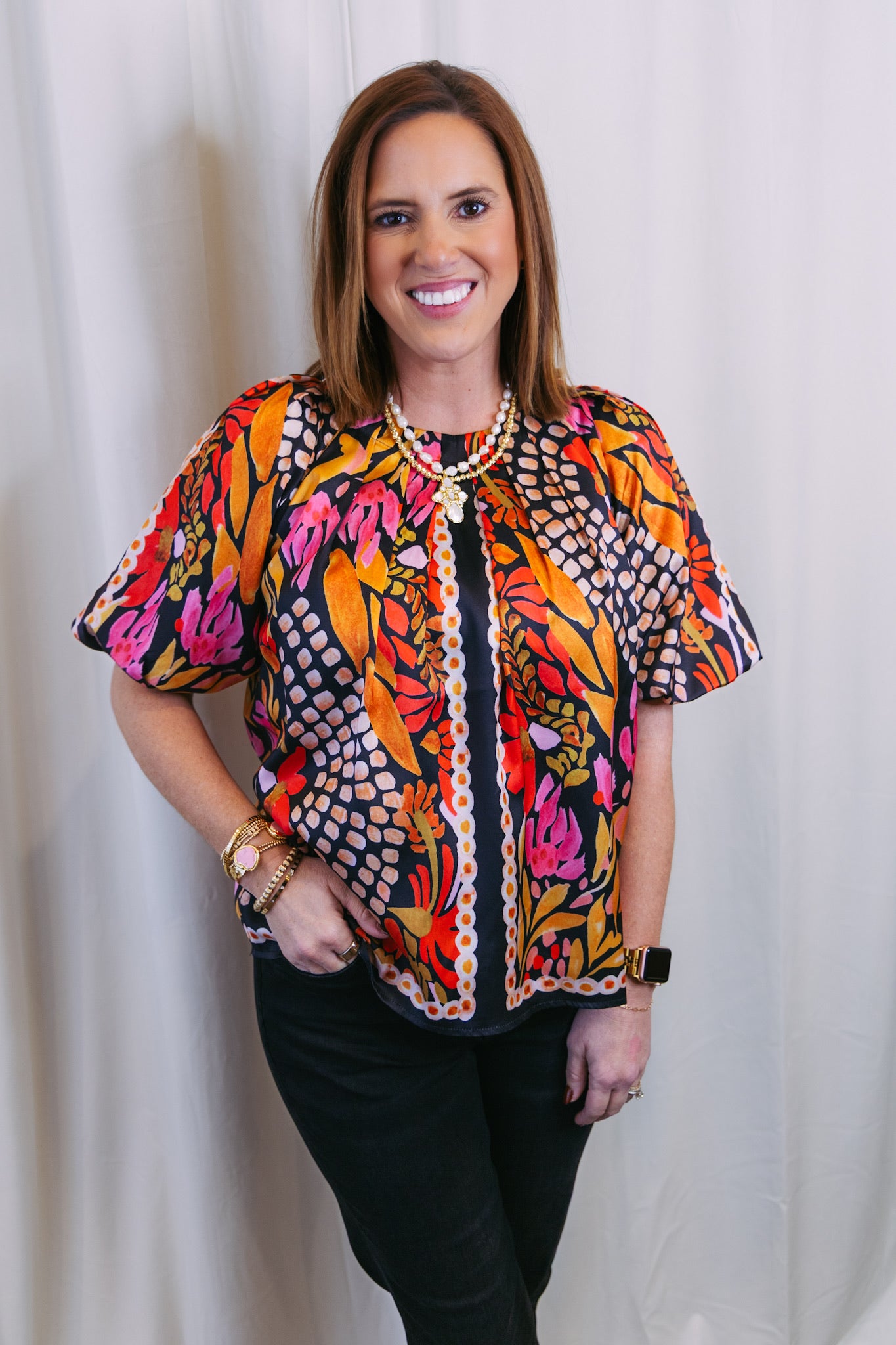 Woman wearing a colorful patterned blouse against a white background